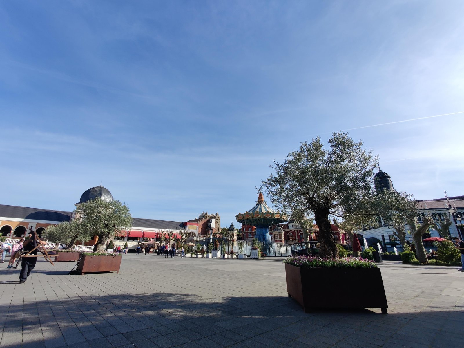 Het plein in Berlin, met de Wellenflug-zweefmolen in het midden en olijfbomen in stalen bakken. Achter de gevels zitten de attractiehallen verstopt. Mooi om te zien hoe Phantasialand met de ruimte om gaat.