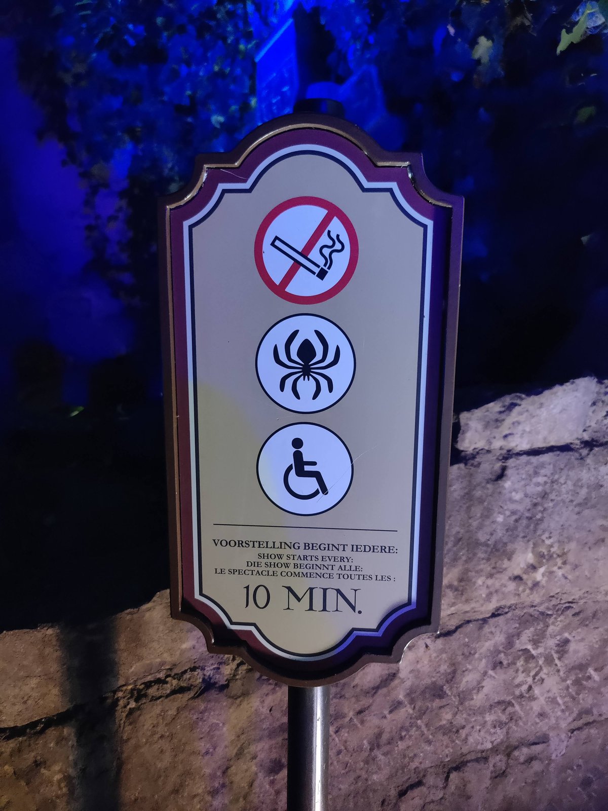 Dit bord is buiten voor het Spookslot te vinden. Het geeft aan dat je binnen niet mag roken, het een griezelige attractie is en dat de attractie rolstoeltoegankelijk is. Onderaan staat dat de show 10 minuten duurt.